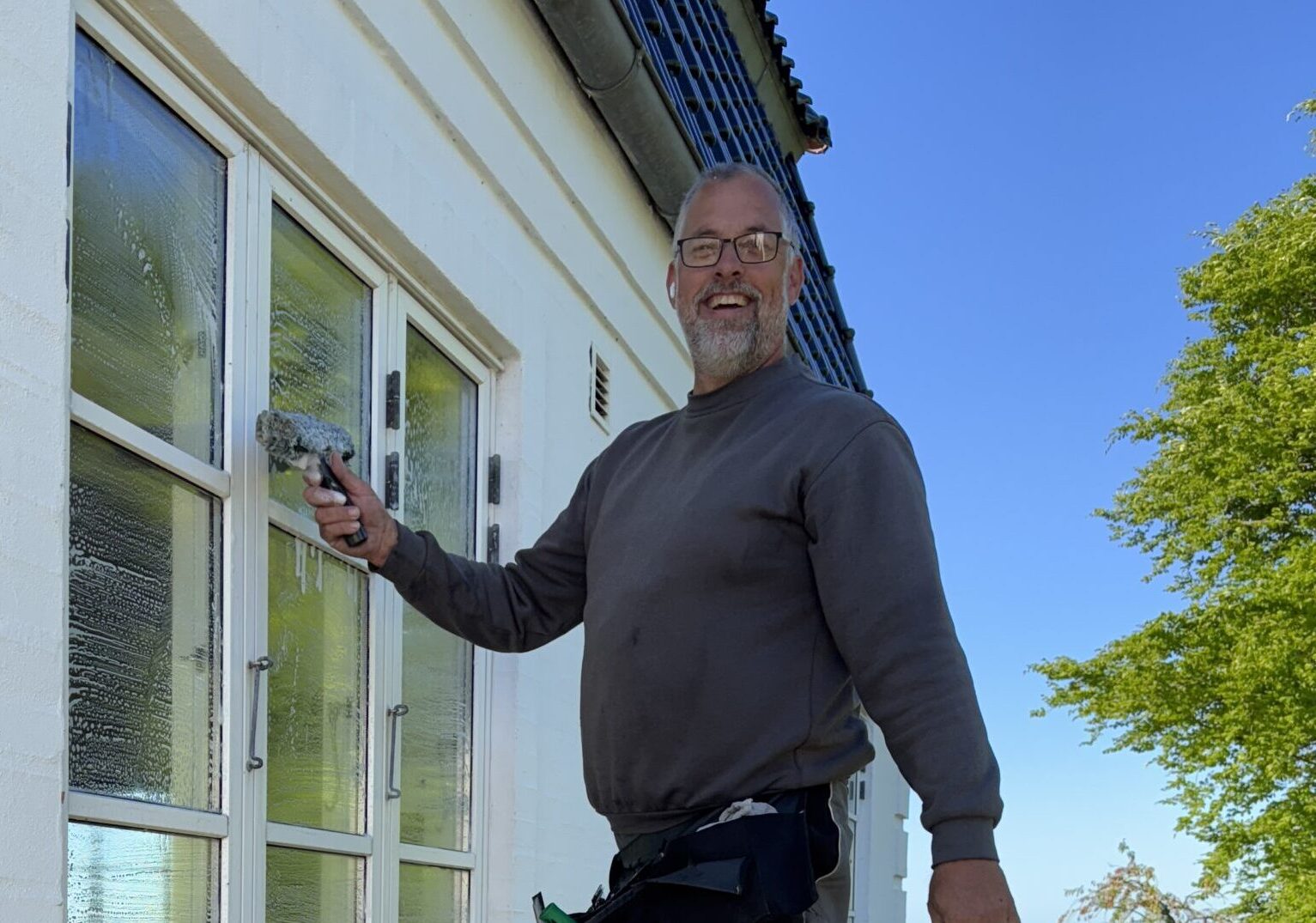 Vinduespudser der vasker vinduer med sæbe og en børste